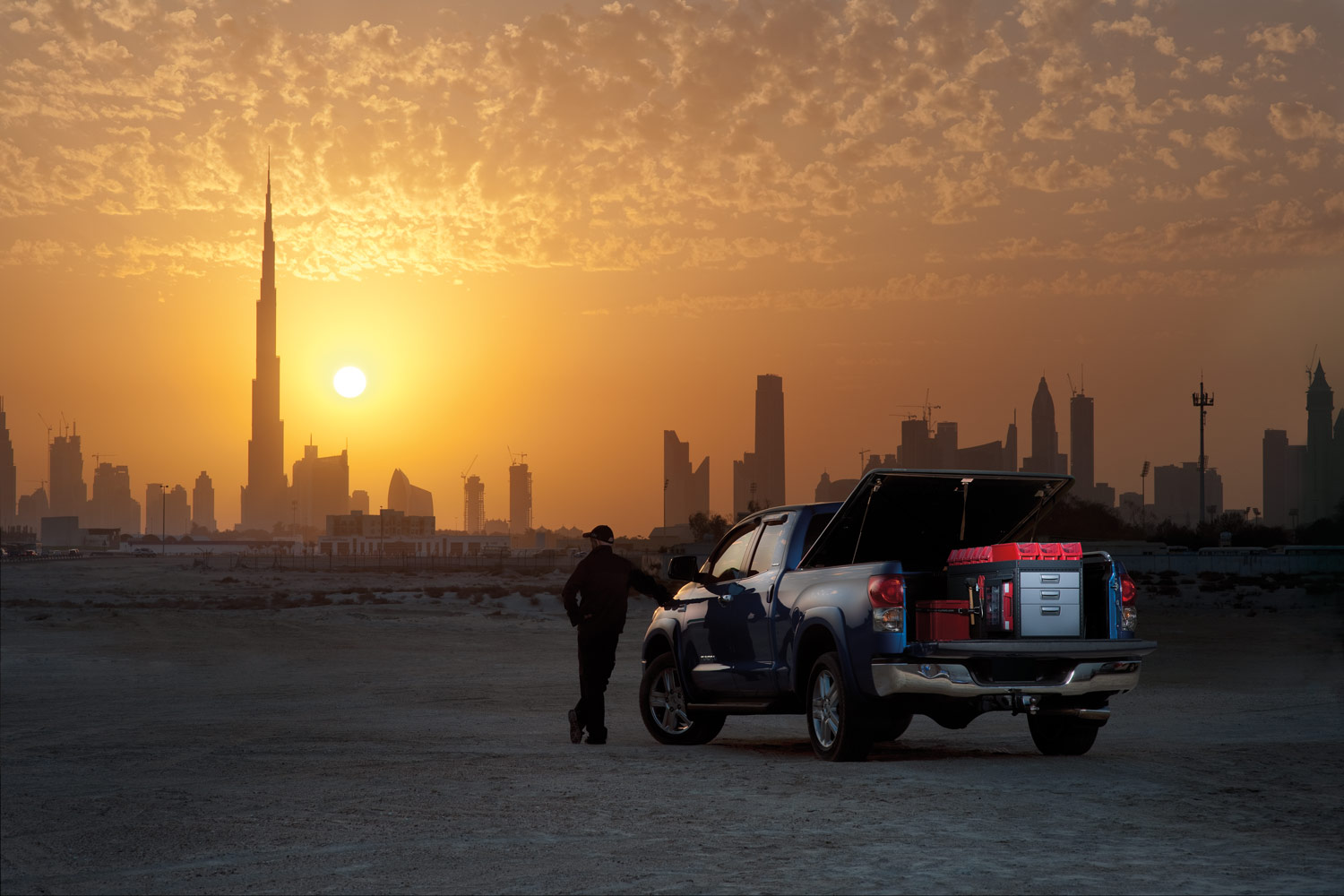 Blauwe pick-up met Modul-System bedrijfswageninrichting, met zonsondergang in de woestijn